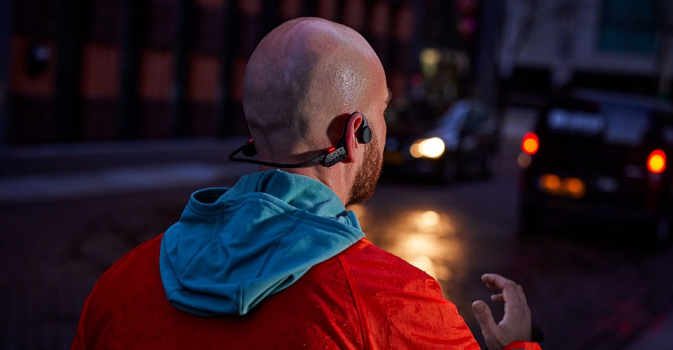 muž s otvorenými slúchadlami na ušiach na preplnenej ulici