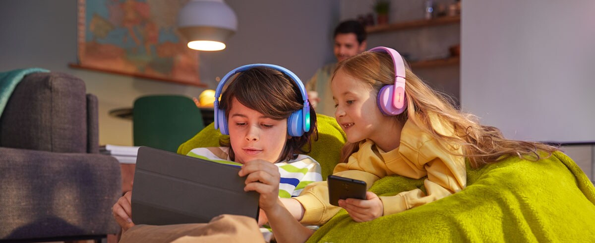 Chlapec a dievča používajú svoje zariadenia a zároveň používajú odolné detské slúchadlá