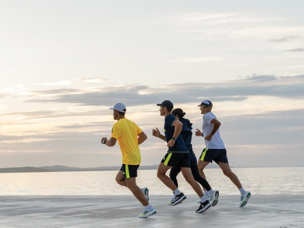 Štyria účastníci behu bežia spolu na pláži.